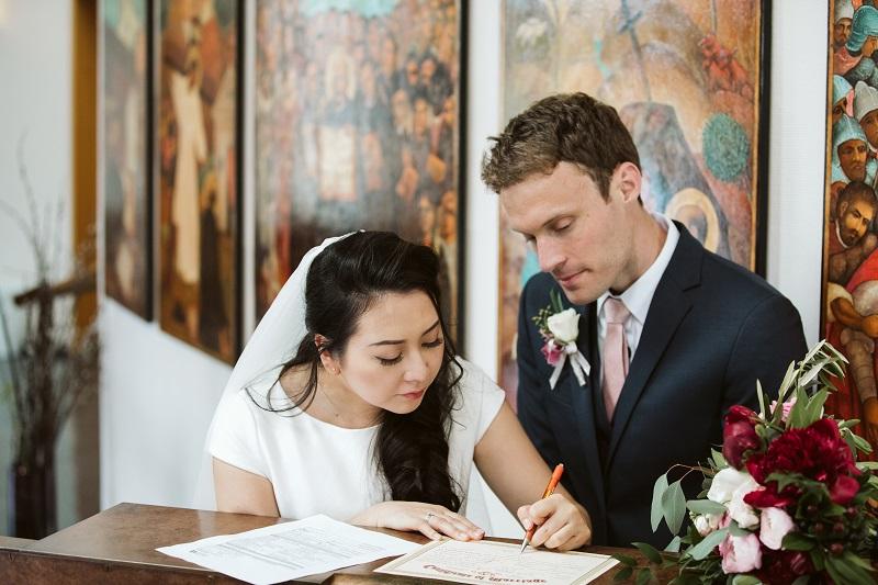 a newlywed couple signs their marriage license in front of the Chapel icons of St. Ignatius